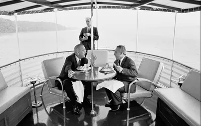 President Johnson has dinner with a guest aboard the USS Sequoia as Secret Service agent Rufus Youngblood stands in the background, 15 July 1965. Photograph by Yoichi Okamoto.